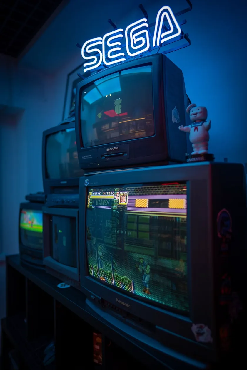 A wall of arcade CRTs under a SEGA sign.