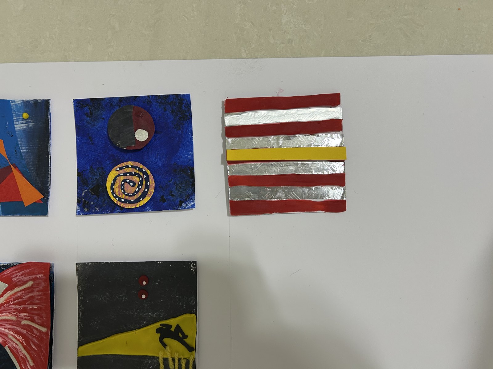Individual tiles in red, blue and yellow clay, paper and foil.